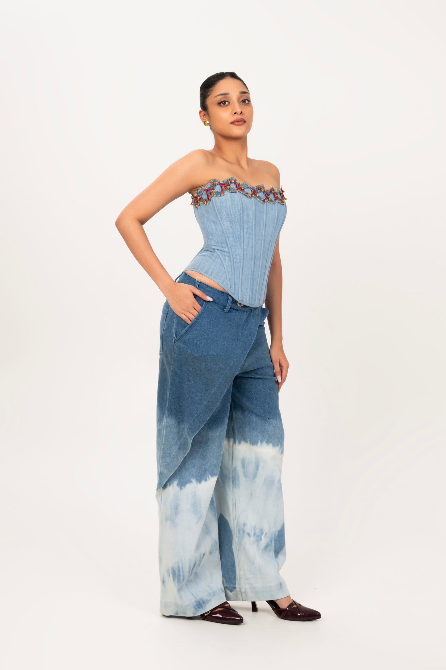 Hand embroidered denim corset and blue bleach-washed draped denim pants.